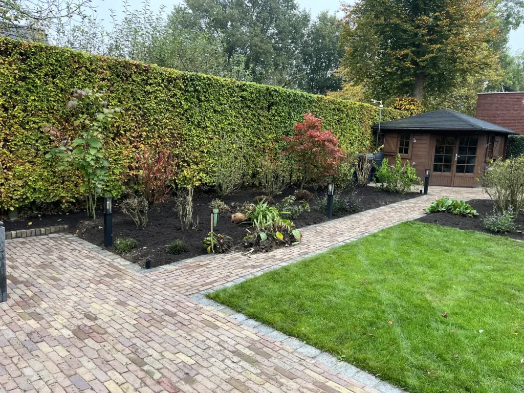Tuin met haag, bestraat pad en tuinhuis