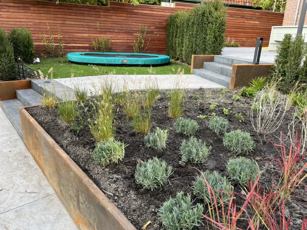 Moderne tuin met cortenstaal en verlaagde trampoline