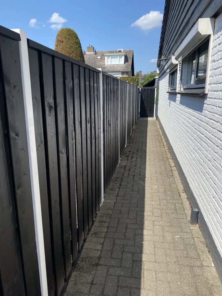 Zwarte schutting met doorkijk en bestrating